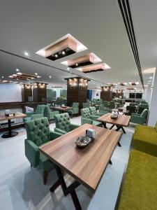 a dining room with tables and green chairs at Hotel Classy Stay in Erbil