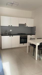 a kitchen with white cabinets and a table with chairs at Appartamento viale della stazione in Spoleto
