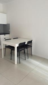 einen weißen Tisch mit schwarzen Stühlen in der Küche in der Unterkunft Appartamento viale della stazione in Spoleto