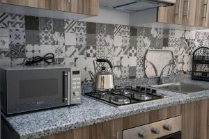 a kitchen with a microwave and a stove top oven at Chaleureux Appartement à louer proche de la gare routière in Tangier