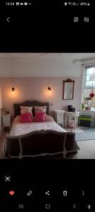 a bedroom with a large bed with pink pillows at Beautiful self-contained annex in Hoylake