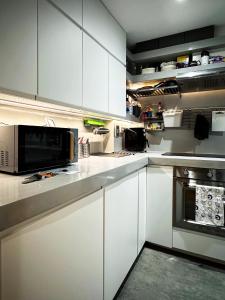 a kitchen with white cabinets and a microwave at David’s Place in EastEnd in London