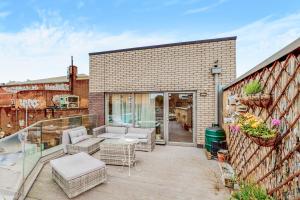 a patio with a couch and chairs on a balcony at Modern and spacious 4 bed house in the city centre in London