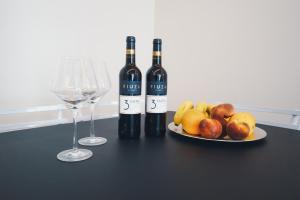 zwei Flaschen Wein und ein Obstteller auf dem Tisch in der Unterkunft Funchal Centrum Apartment in Funchal