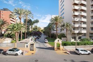 uma rua com carros estacionados e palmeiras e um edifício em Bajondillo Playa em Torremolinos