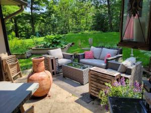 un patio con sofás, una mesa y un jarrón en Anthropocene Jewel Cottage, en Milton