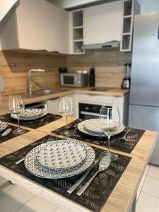 a kitchen with two plates and wine glasses on a counter at Ti MACLOA - Appartement les pieds dans l'eau in Sainte-Anne