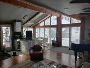 ein Wohnzimmer mit einem Tisch und eine Küche mit Fenstern in der Unterkunft Anthropocene Jewel Cottage in Milton