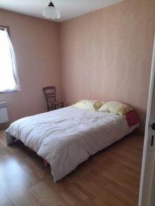 una camera da letto con un letto e un piumone bianco di La belle maisonette a Montmorillon