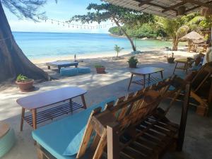 a beach with tables and benches and the ocean at KAMAKU Bungalows in Koh Rong Sanloem