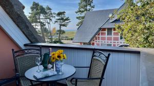 a table with flowers and wine glasses on a balcony at Haus Strandgut FW 6 in Ahrenshoop