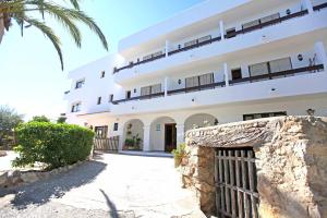 a large white building with a gate and a palm tree at Hostal Marblau Ibiza in Ibiza Town