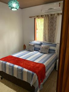 een slaapkamer met een bed met blauwe en witte lakens en een raam bij Chalé Quartzo no Recanto Diamantina entre Palmeiras e Capão in Palmeiras