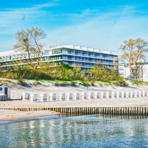 a building on the beach next to a body of water at Seaside Park Hotel in Kołobrzeg