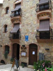 a stone building with balconies and a sign in front of it at L'Hostalet in Arboli