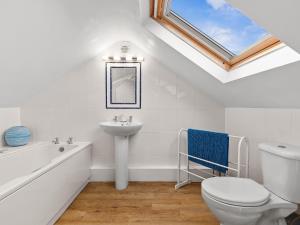 a bathroom with a sink toilet and a skylight at Crab Cottage in Morfa Nefyn