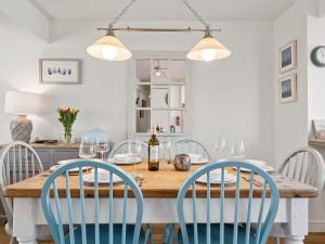 a dining room with a wooden table and blue chairs at Crab Cottage in Morfa Nefyn