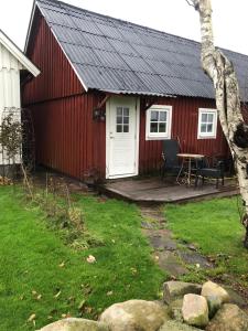 un granero rojo con terraza y mesa en Havsnära lantligt boende, en Glommen