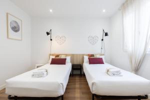 2 camas en una habitación con paredes blancas en INSIDEHOME Apartments - La Casita de Oscar, en Palencia