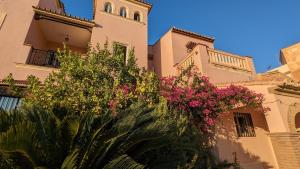 um edifício com uma torre de relógio com flores cor-de-rosa em Casa Monte Victoria em Málaga