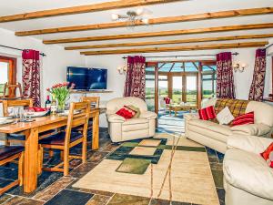 a living room with couches and a table and chairs at Beacon Cottage in Llanrian