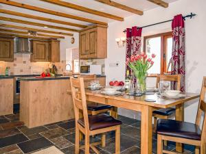a kitchen with a wooden table and chairs and a kitchen with a counter at Beacon Cottage in Llanrian
