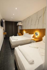 um quarto de hotel com duas camas com lençóis brancos em Aglon Twin's Hotel em Vlorë