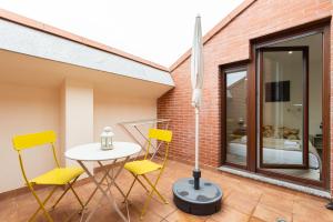 eine Terrasse mit gelben Stühlen, einem Tisch und einem Fenster in der Unterkunft INSIDEHOME Apartments - La Casita de Álex in Palencia