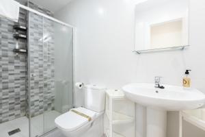 Baño blanco con aseo y lavamanos en INSIDEHOME Apartments - La Casita de Álex en Palencia
