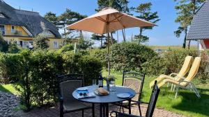 a table and chairs with an umbrella on a patio at Haus Strandgut FW 2 in Ahrenshoop