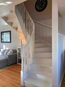 a white staircase in a living room with a clock at Mølleråsen Apartment in Sandefjord