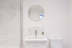 a white bathroom with a sink and a mirror at The Dovecote - Collins Farm in Bristol