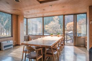 Cette chambre comprend une grande table en bois et des fenêtres. dans l'établissement 豊島ロッヂooバス停浅貝上前, à Yuzawa