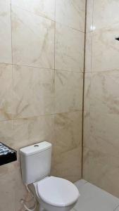 a bathroom with a toilet and a tiled wall at Oásis da Praia in Caucaia