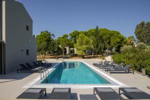 a swimming pool with lounge chairs next to a building at Alekos Beach Houses-Akrotiri Suites in Kounopetra