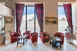 a waiting room with chairs and tables and large windows at Hôtel Terminus in Grenoble