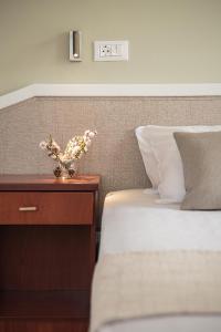 a bed with a vase of flowers on a night stand at Artemis Apartments in Stalos