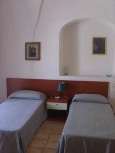 ランペドゥーザにあるLe Pietre Di Lampedusaのベッドルーム1室(ベッド2台、ランプ付きテーブル付)