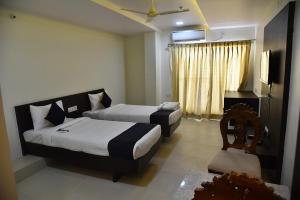 a hotel room with two beds and a television at Swarna Palace in Siddipet