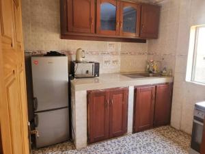 eine Küche mit Holzschränken und einem Kühlschrank in der Unterkunft Olympus House in Jaunde