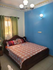 a bedroom with a bed with a blue wall at Olympus House in Yaoundé