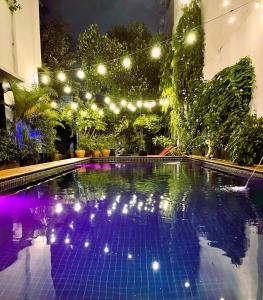 a swimming pool with lights in a garden at night at Birdcage Boutique in Phnom Penh