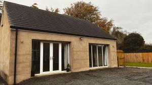 een kleine schuur met een zwart dak bij Lisnevenagh Cottage in Ballymena