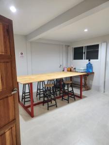 - une cuisine avec une table en bois et quelques tabourets de bar dans l'établissement No.9 Hostel kanchanaburi, à Ban Don Rak