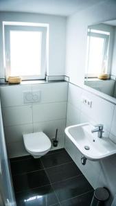 a white bathroom with a toilet and a sink at Ferienhaus "Schmale Gisela" bis zu 6 Personen mit Garten und Parkplätzen in Seligenstadt +11 photos