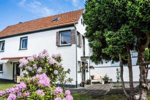 a white house with flowers in front of it at Ferienhaus "Schmale Gisela" bis zu 6 Personen mit Garten und Parkplätzen in Seligenstadt