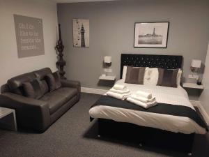 a bedroom with a bed and a leather couch at Q - Accomodation in Blackpool