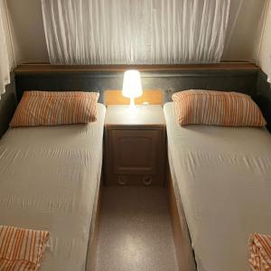 a small room with two beds and a table with a lamp at WMC BUSCHMANN camping-in-venedig Wohnwagenvermietung at UNION LIDO Cavallino in Cavallino-Treporti