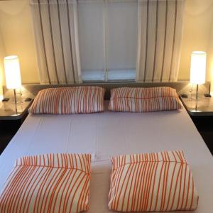 un grande letto bianco con due cuscini e due lampade di WMC BUSCHMANN camping-in-venedig Wohnwagenvermietung at UNION LIDO Cavallino a Cavallino-Treporti