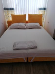 a large bed with white sheets and orange pillows at Студио Ели - Пловдив in Plovdiv